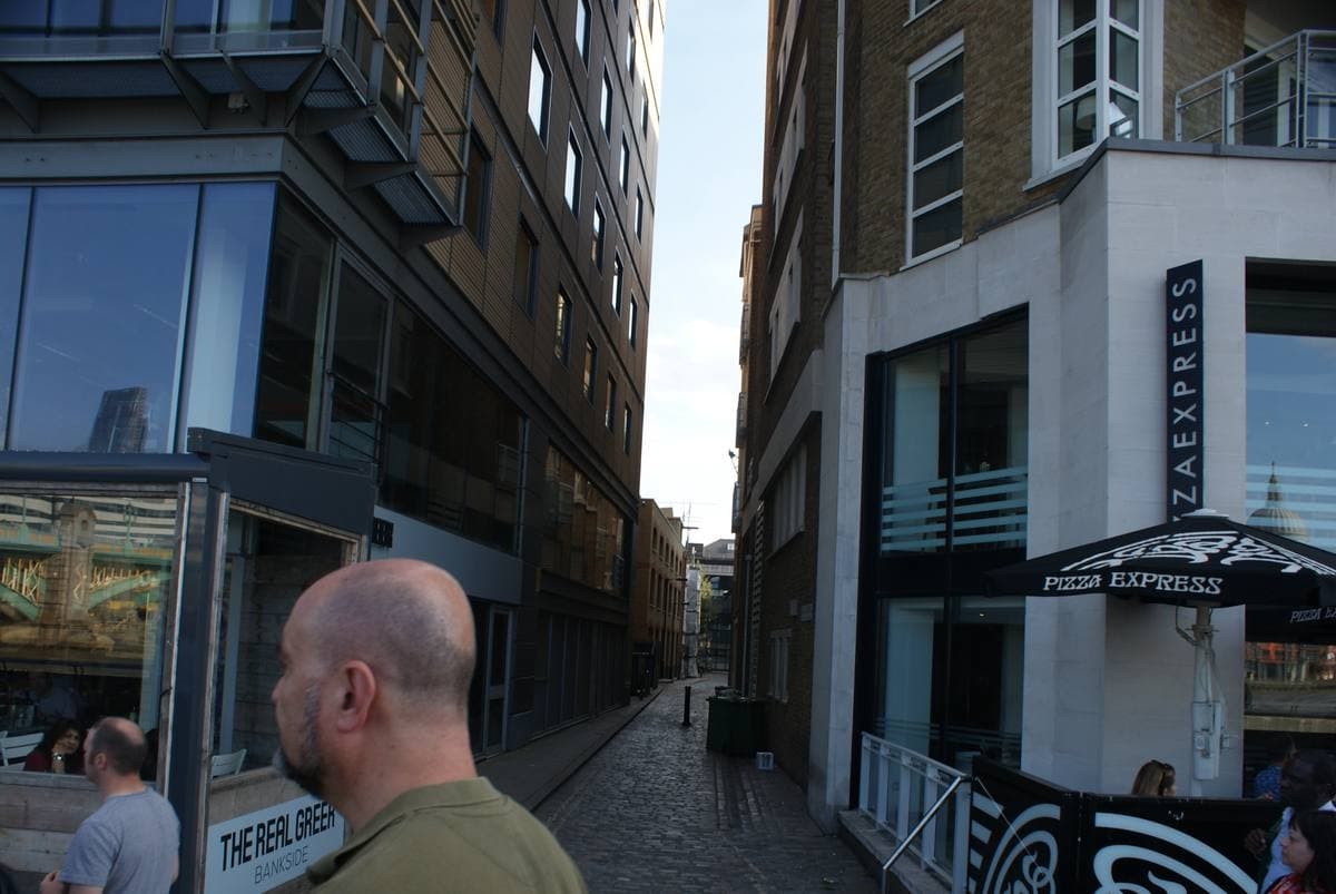A narrow street running away from the river between brick buildings