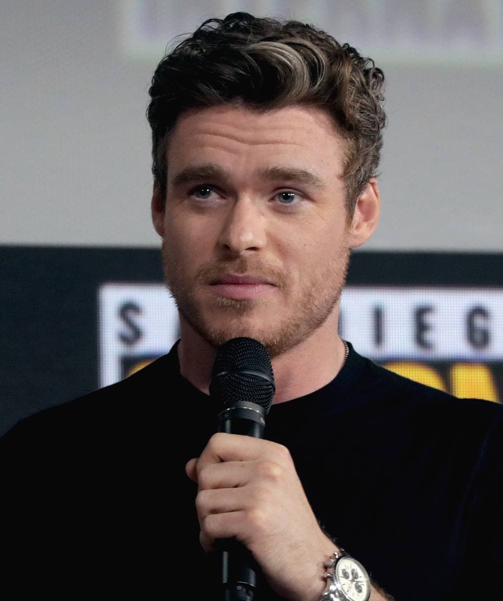 Richard Madden, dark hair and beard, speaking at a microphone