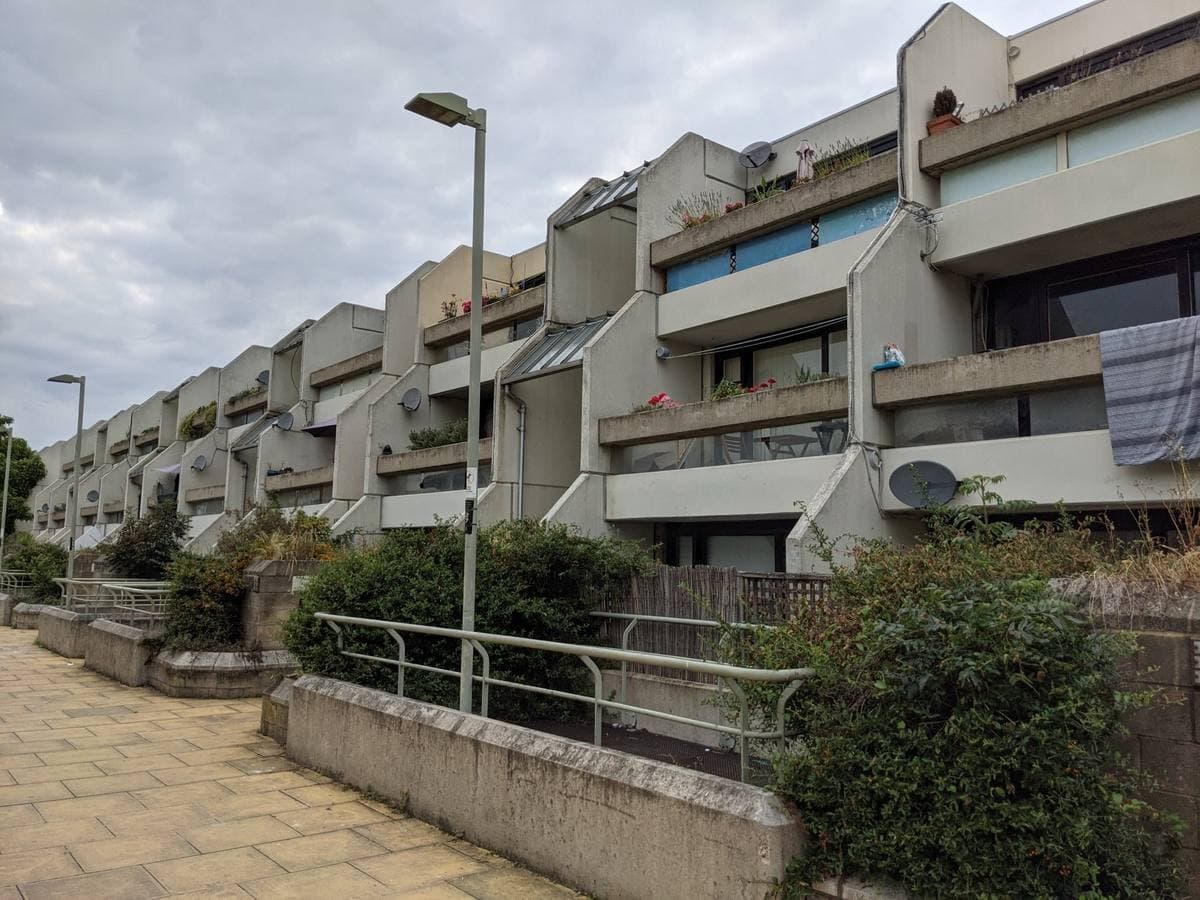 A stepped concrete terrace of flats along a pedestrian street