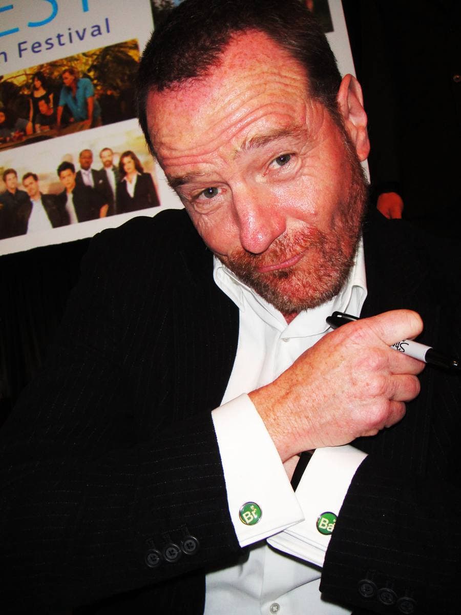 Bryan Cranston grinning, showing his cufflinks