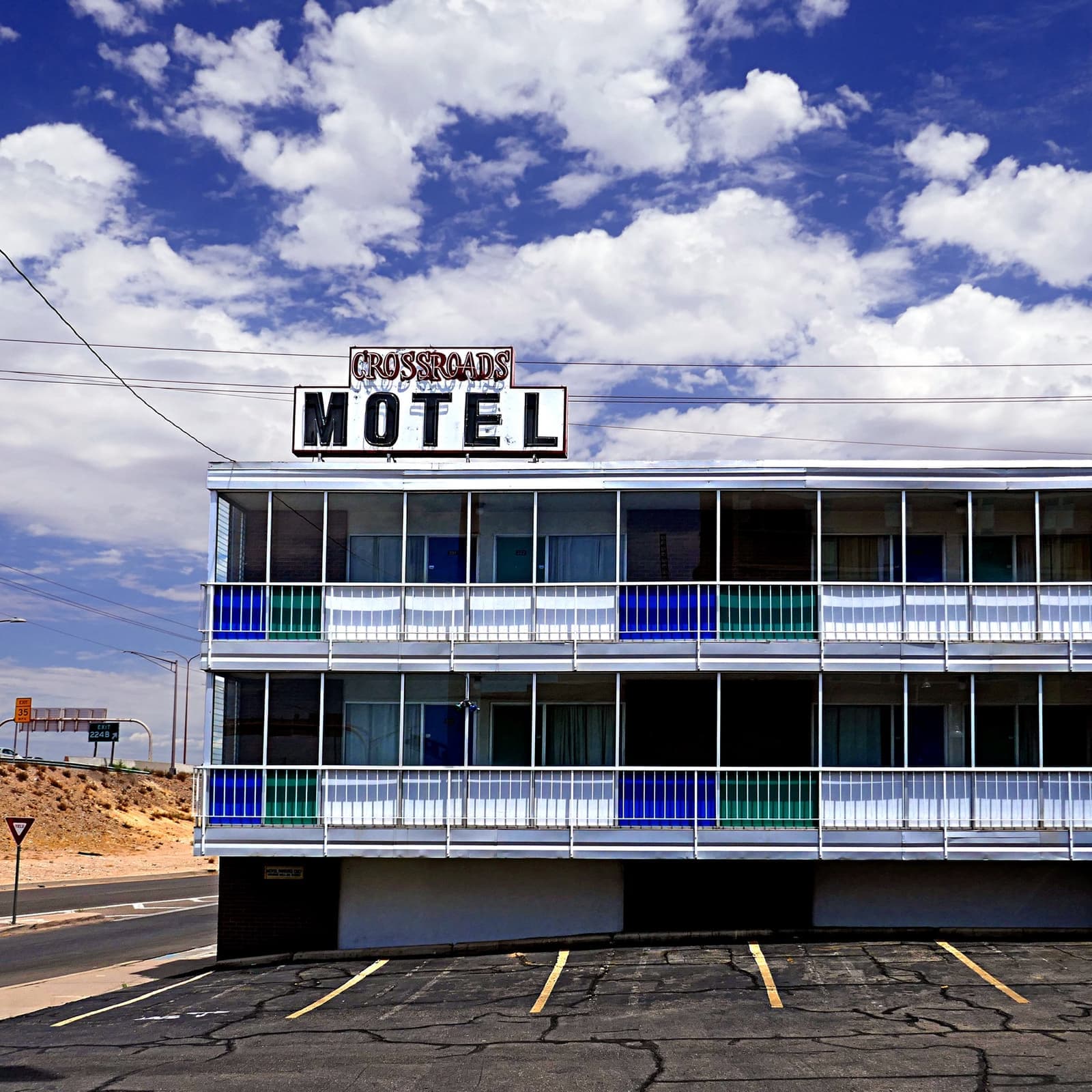 A three-storey motel with blue and green balcony panels and a red Motel sign