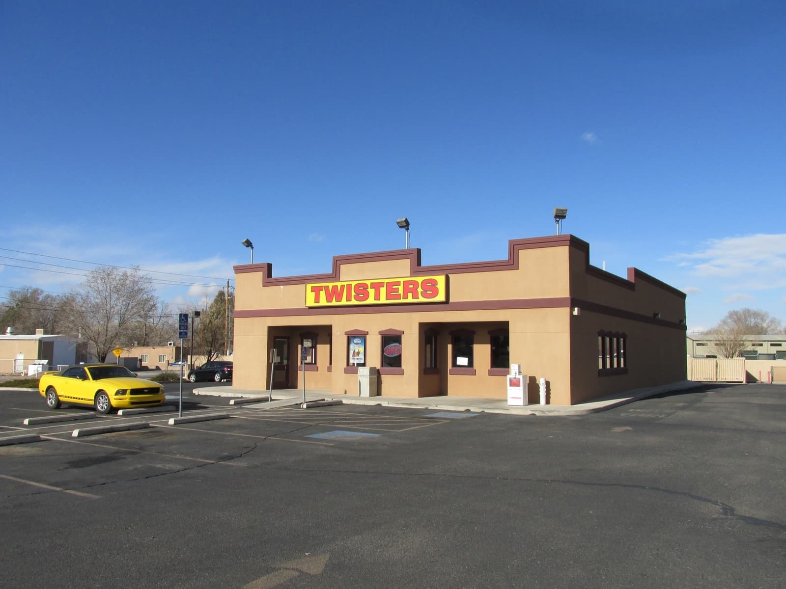 A tan fast-food restaurant with a red and yellow Twisters sign