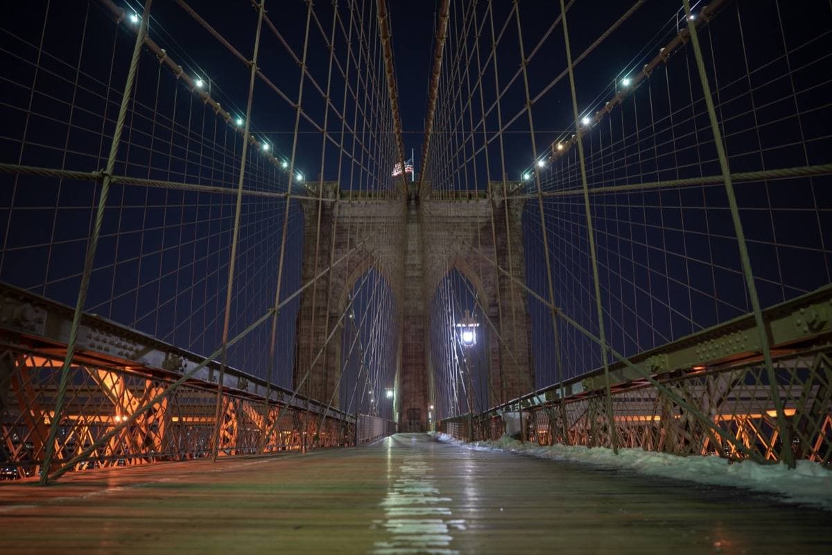 The Brooklyn Bridge’s stone towers and cables lit at night