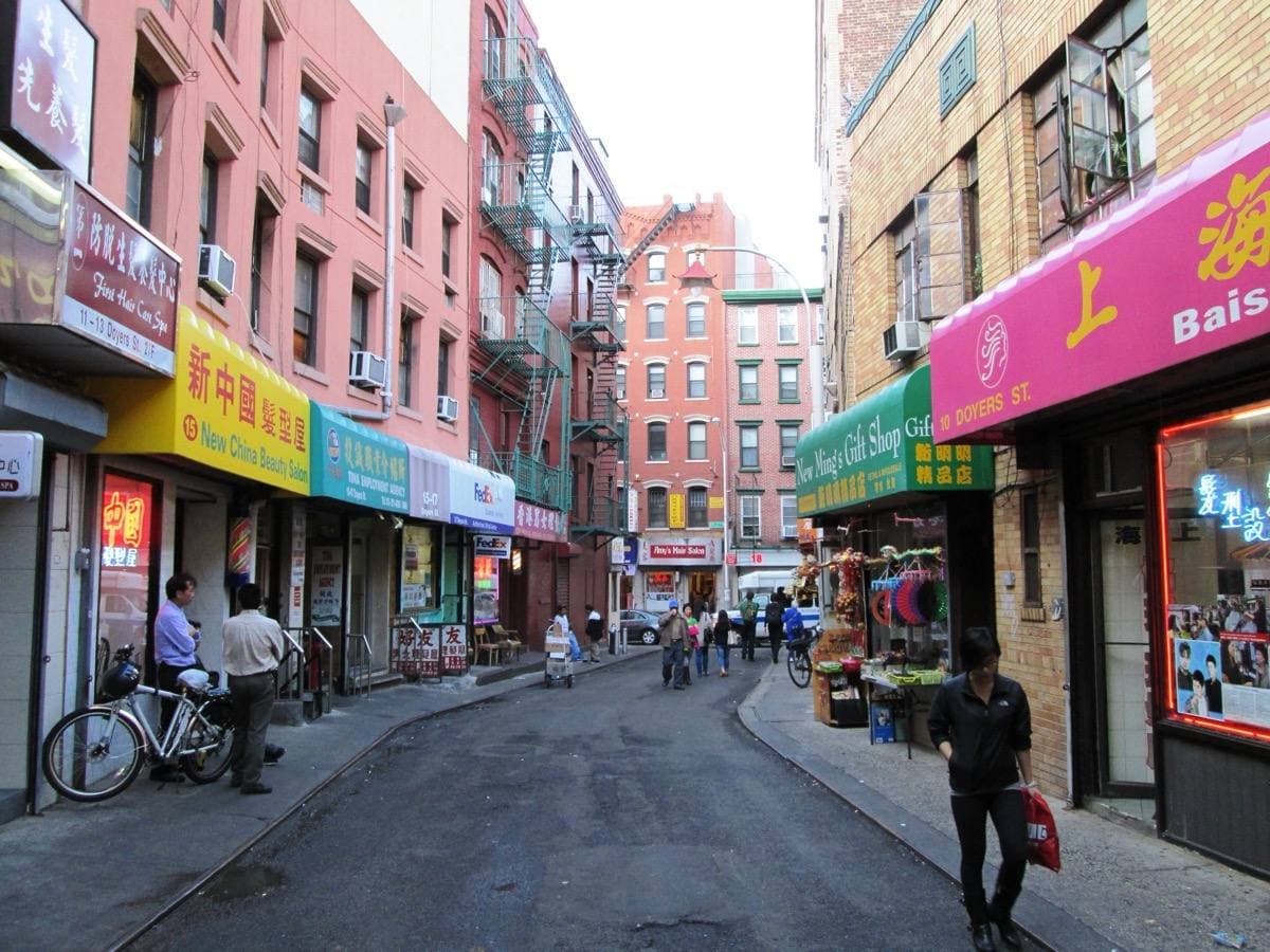 A narrow curving street in Chinatown lined with shop signs