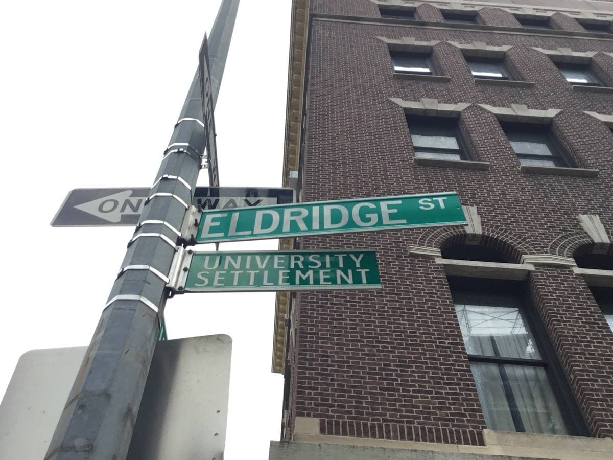 A green Eldridge Street sign against Lower East Side buildings