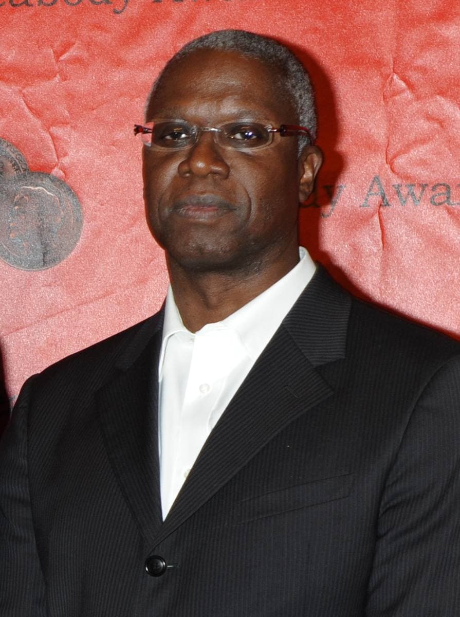 A bald man in a dark suit and tie smiling slightly
