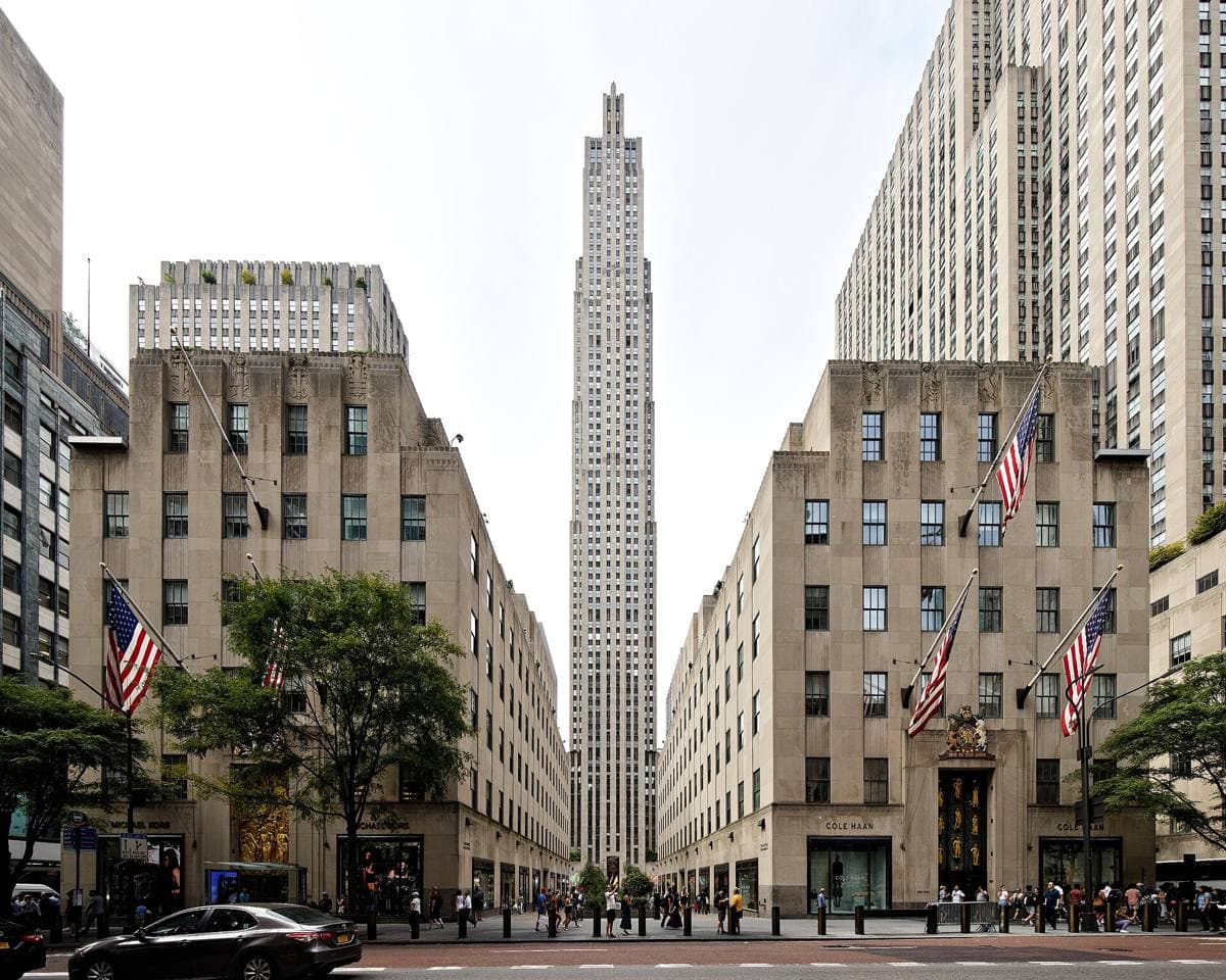 A tall stepped Art Deco limestone tower behind the low buildings of Rockefeller Center