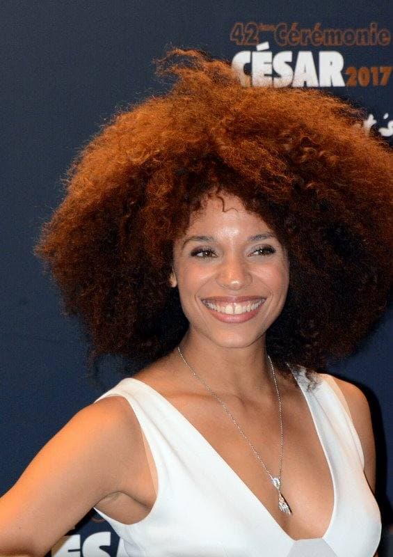 Stéfi Celma smiling, her hair a wide natural halo, at a César photocall