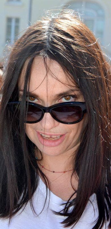 Béatrice Dalle in dark glasses, long dark hair, smiling