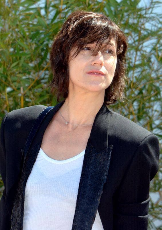 Charlotte Gainsbourg in a black jacket, against tall grasses