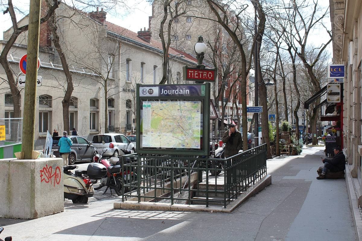 A métro entrance with a green railing and a map, on a busy pavement