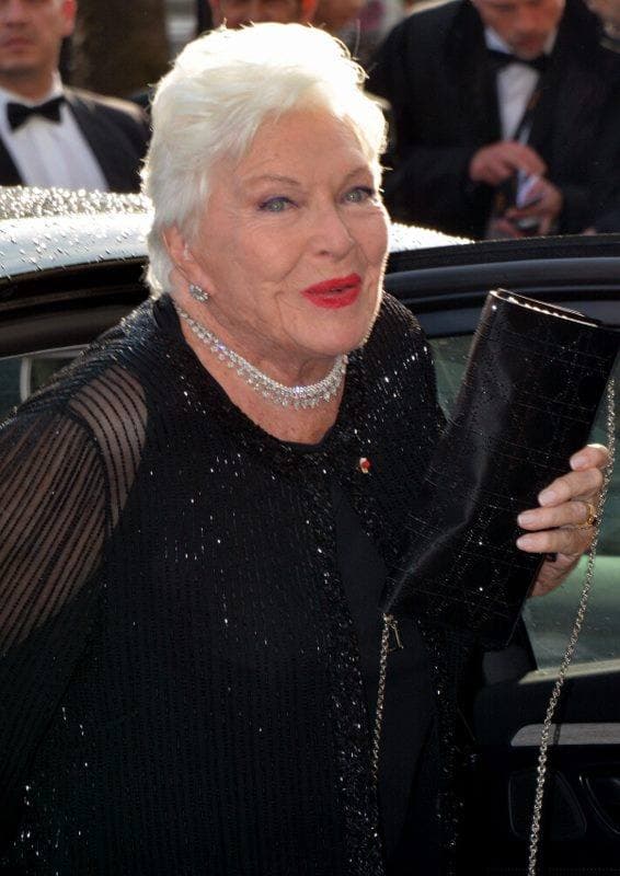 Line Renaud, white hair, in black with pearls, stepping from a car