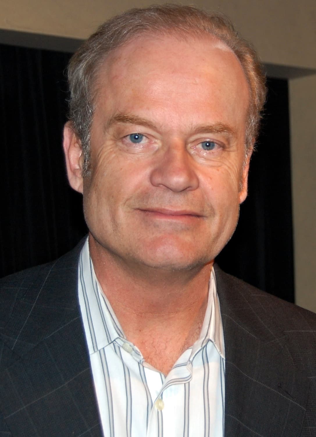 Kelsey Grammer in a dark jacket and striped shirt, looking at the camera
