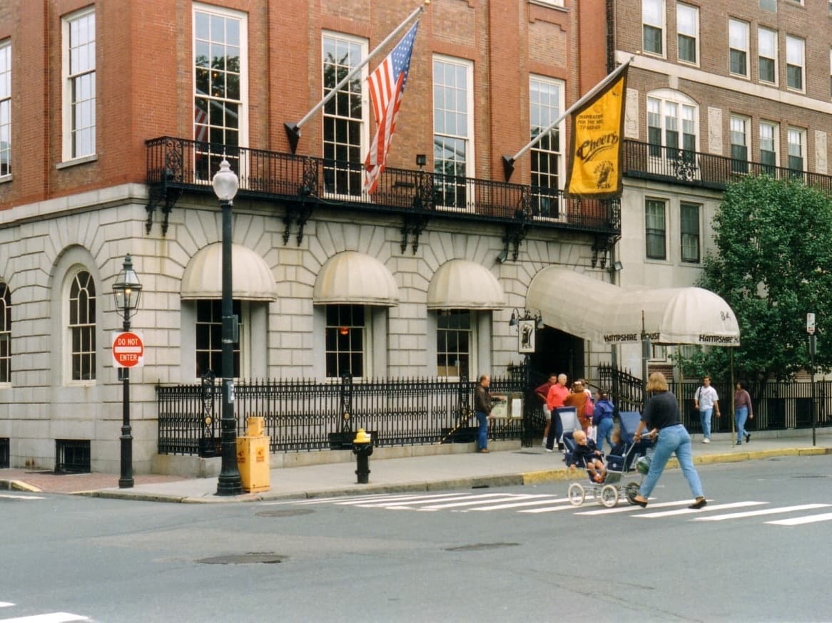The corner of 84 Beacon Street in 1994, a stroller crossing in front of the awnings