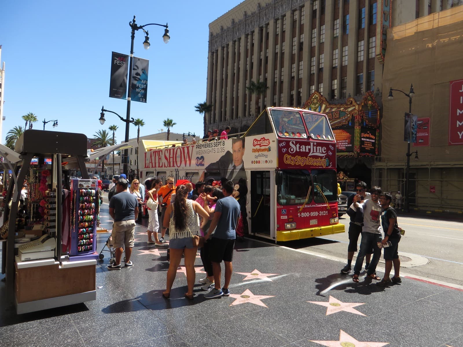 Visitors on a black terrazzo pavement set with pink stars on Hollywood Boulevard