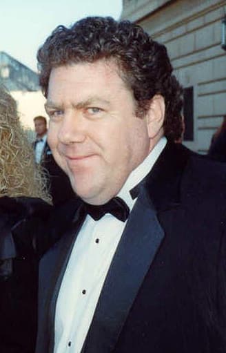 George Wendt with curly dark hair in a tuxedo and bow tie