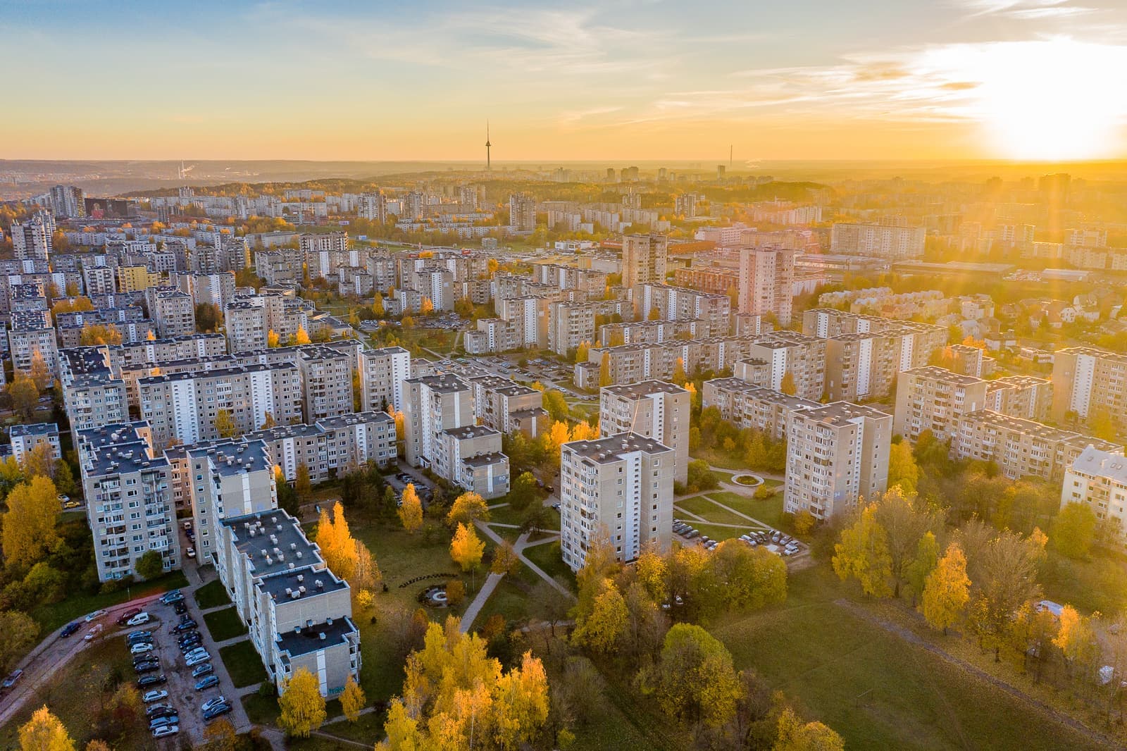 Rows of pale apartment blocks in Fabijoniškės lit by a low sun
