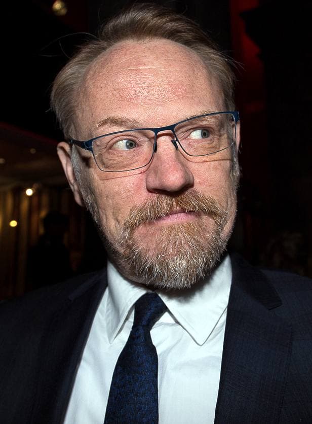 Jared Harris in glasses and a dark suit, glancing sideways
