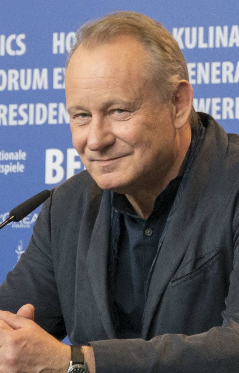 Stellan Skarsgård smiling at a press conference microphone