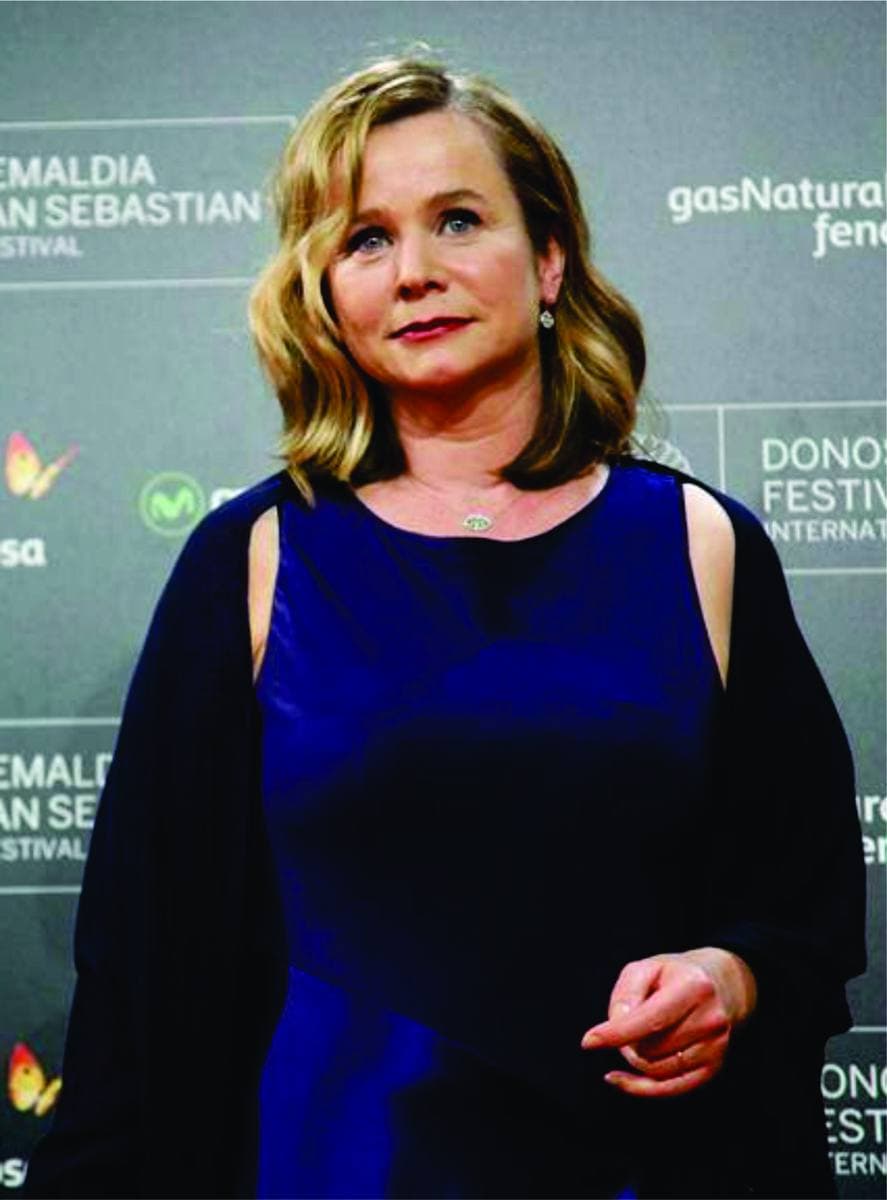 Emily Watson in a dark blue dress in front of a festival backdrop