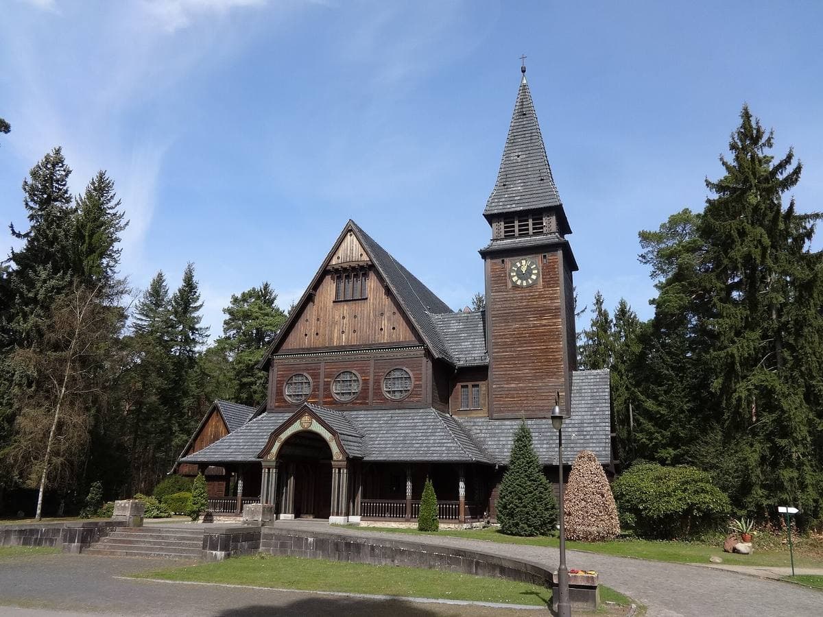 The timber chapel at the end of a path, framed by fir trees