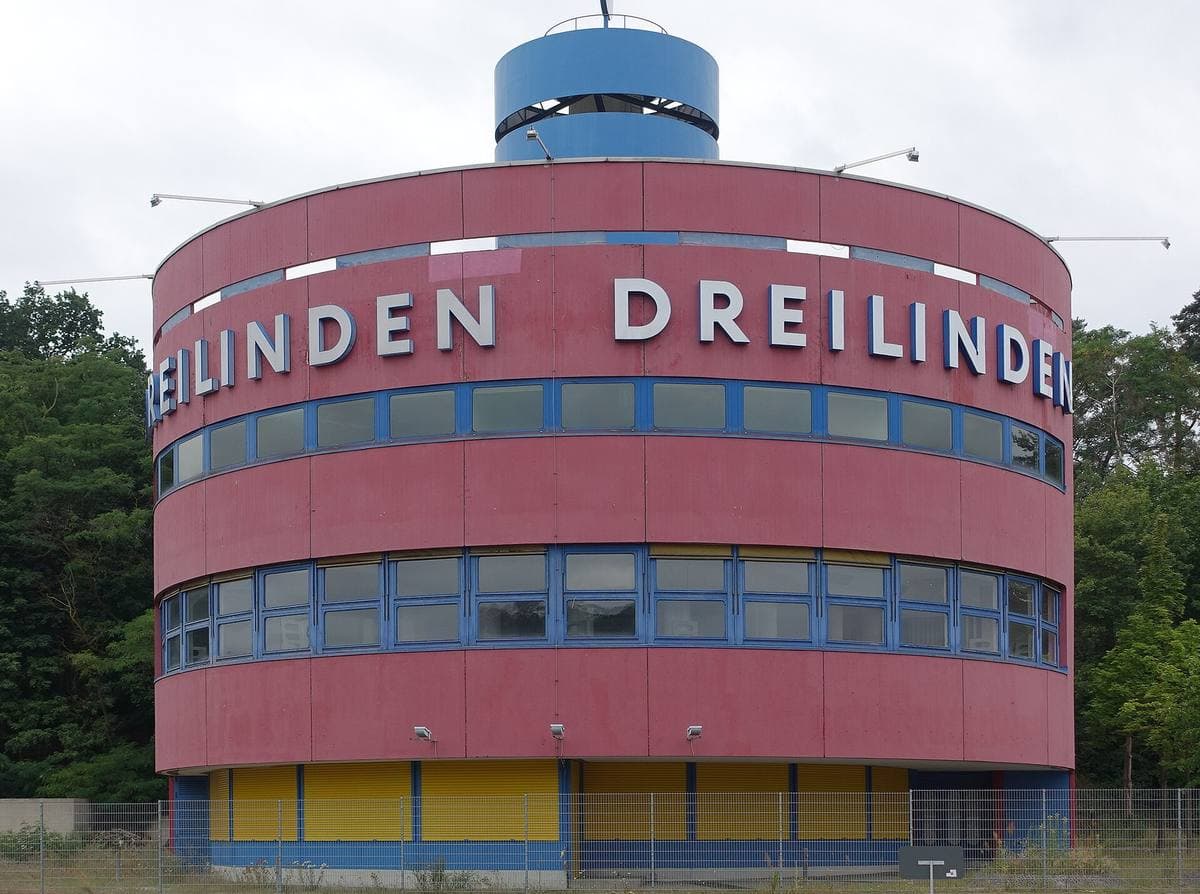 A round red building with blue and yellow bands and the word Dreilinden in white letters round the top
