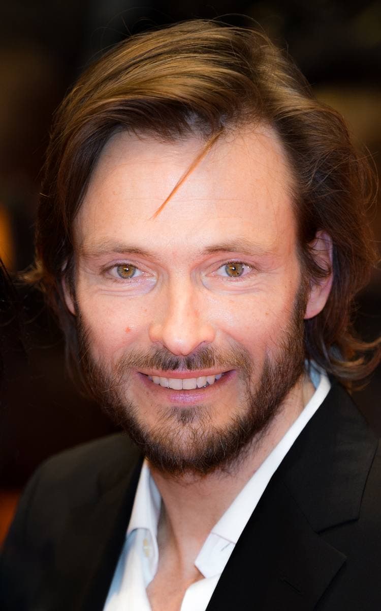 Andreas Pietschmann, bearded, smiling on a red carpet