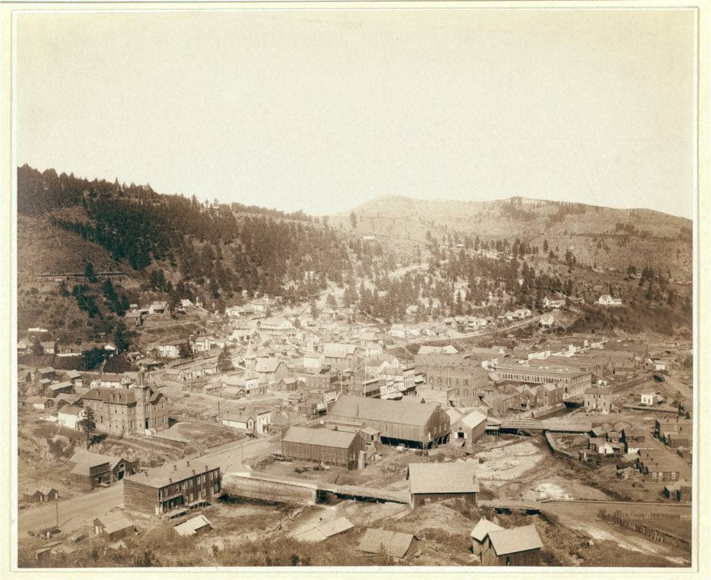 A town of roofs filling a valley floor between wooded hills
