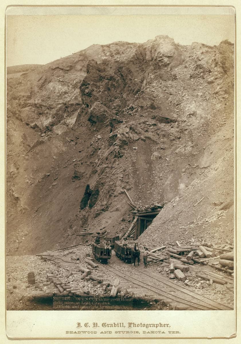 A steep bare hillside quarried open, with a timber structure at its foot
