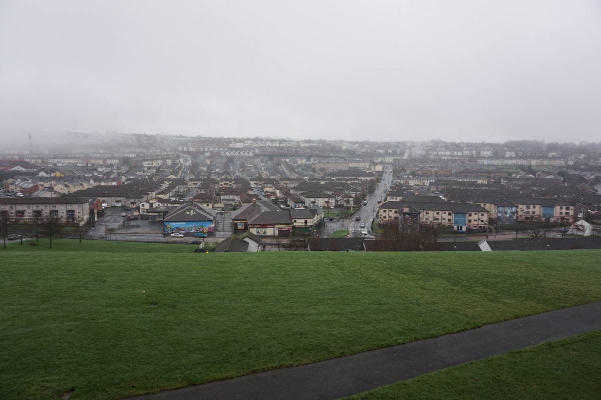 Rooftops of terraced streets spreading down a valley under grey sky