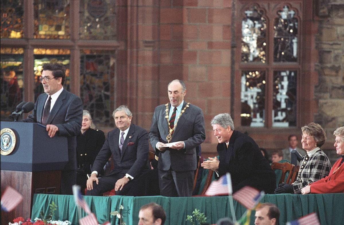 A platform in front of the Guildhall’s tall windows, a man at a lectern with the presidential seal, dignitaries seated behind