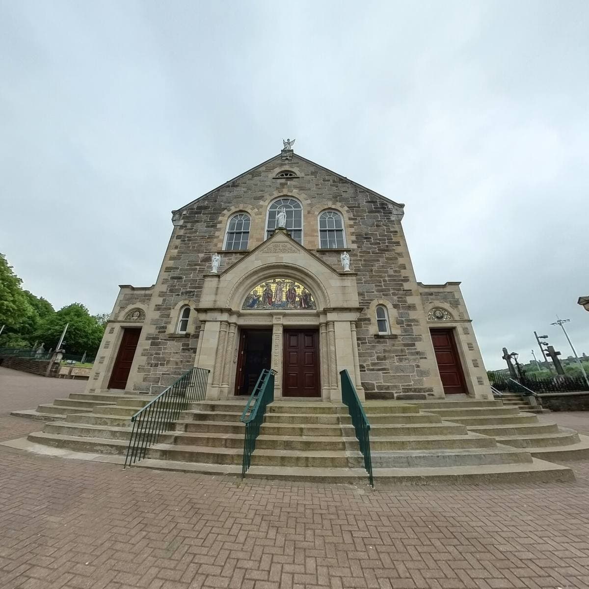 A classical stone church front with steps and three doors