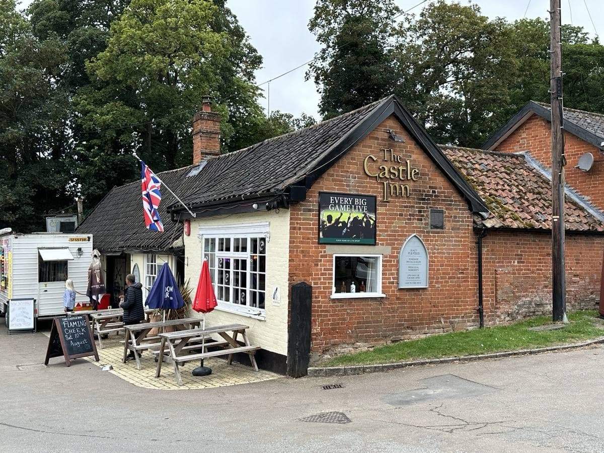 A small brick pub with a pitched tiled roof, picnic tables and a Union flag outside