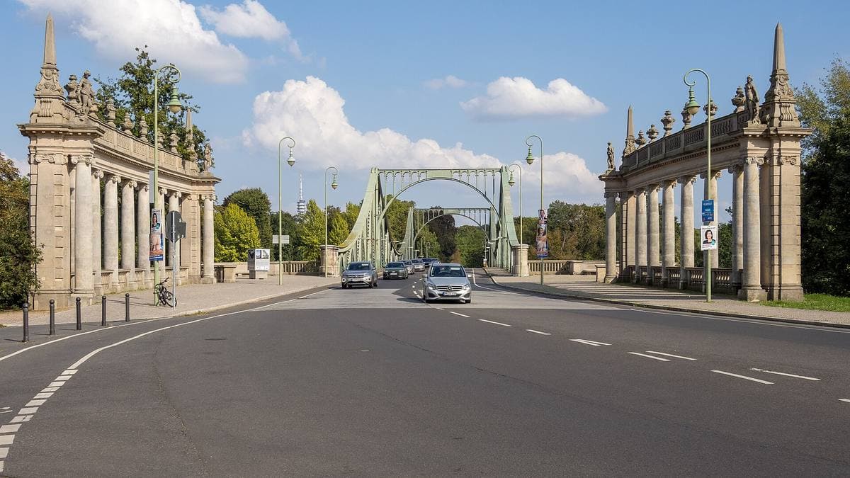 A green steel bridge between two colonnades, with traffic