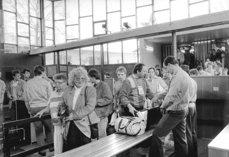 Travellers with bags at a passport control counter in a station hall