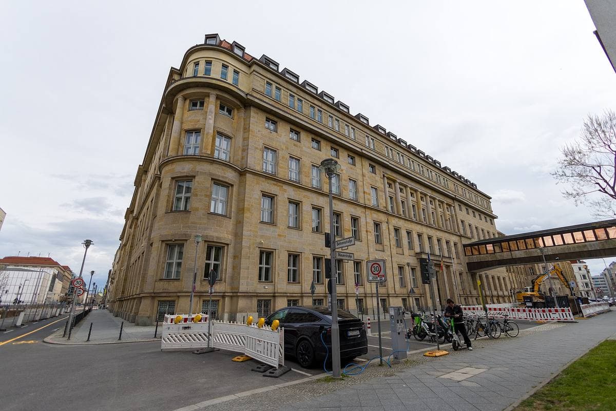 A sandstone office block on a street corner with a covered bridge to the next block