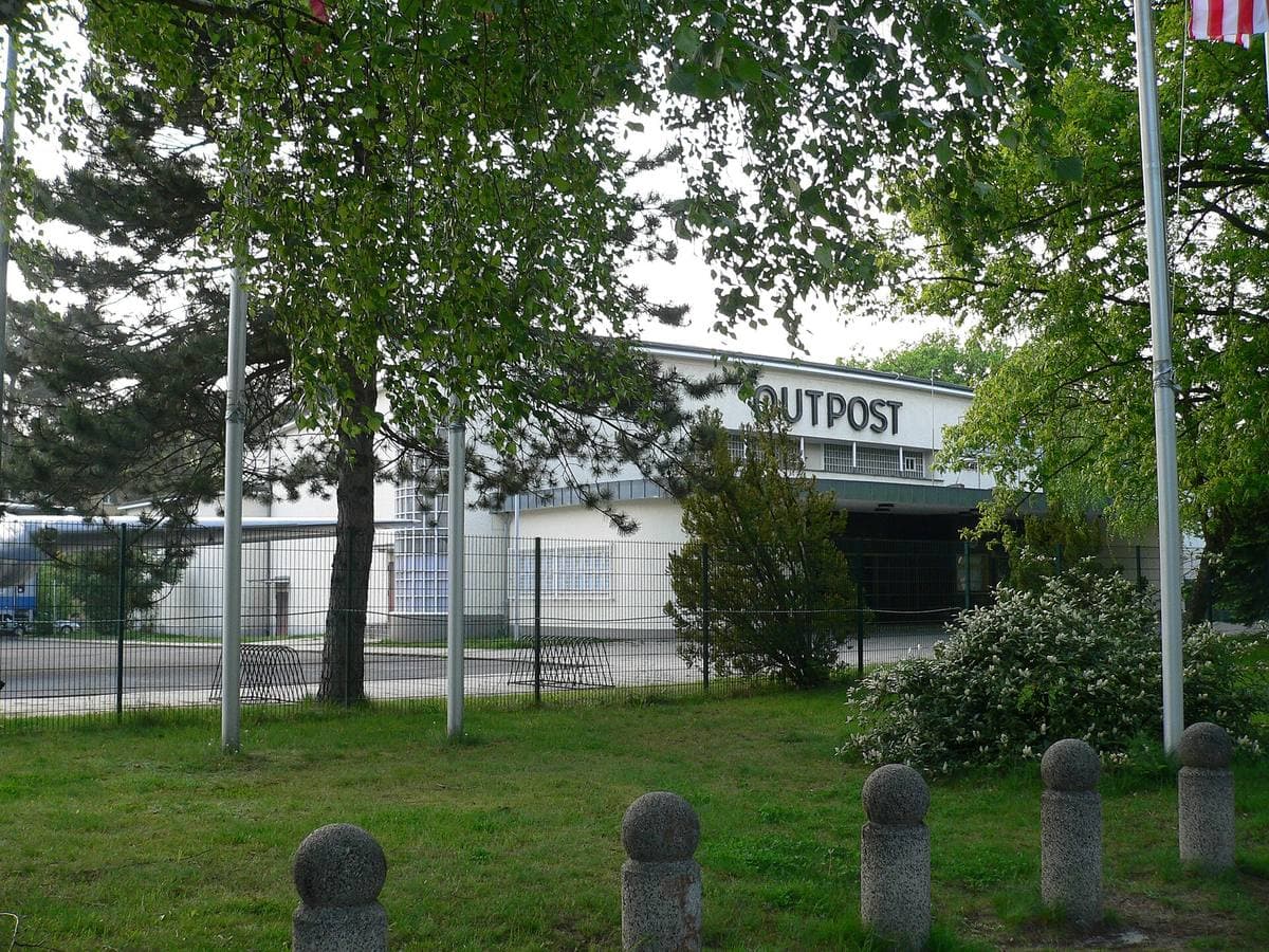 A low building with OUTPOST in big letters behind trees