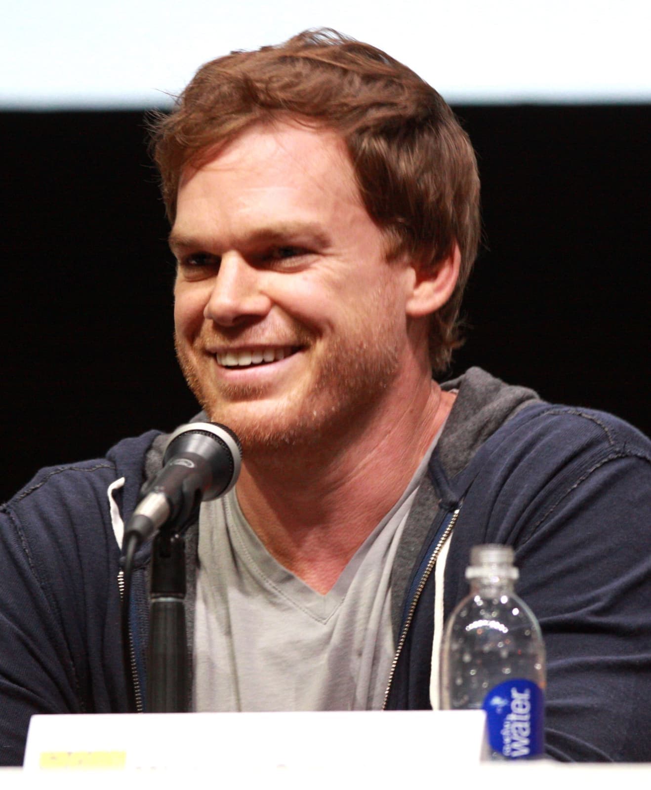 Michael C. Hall smiling at a panel microphone