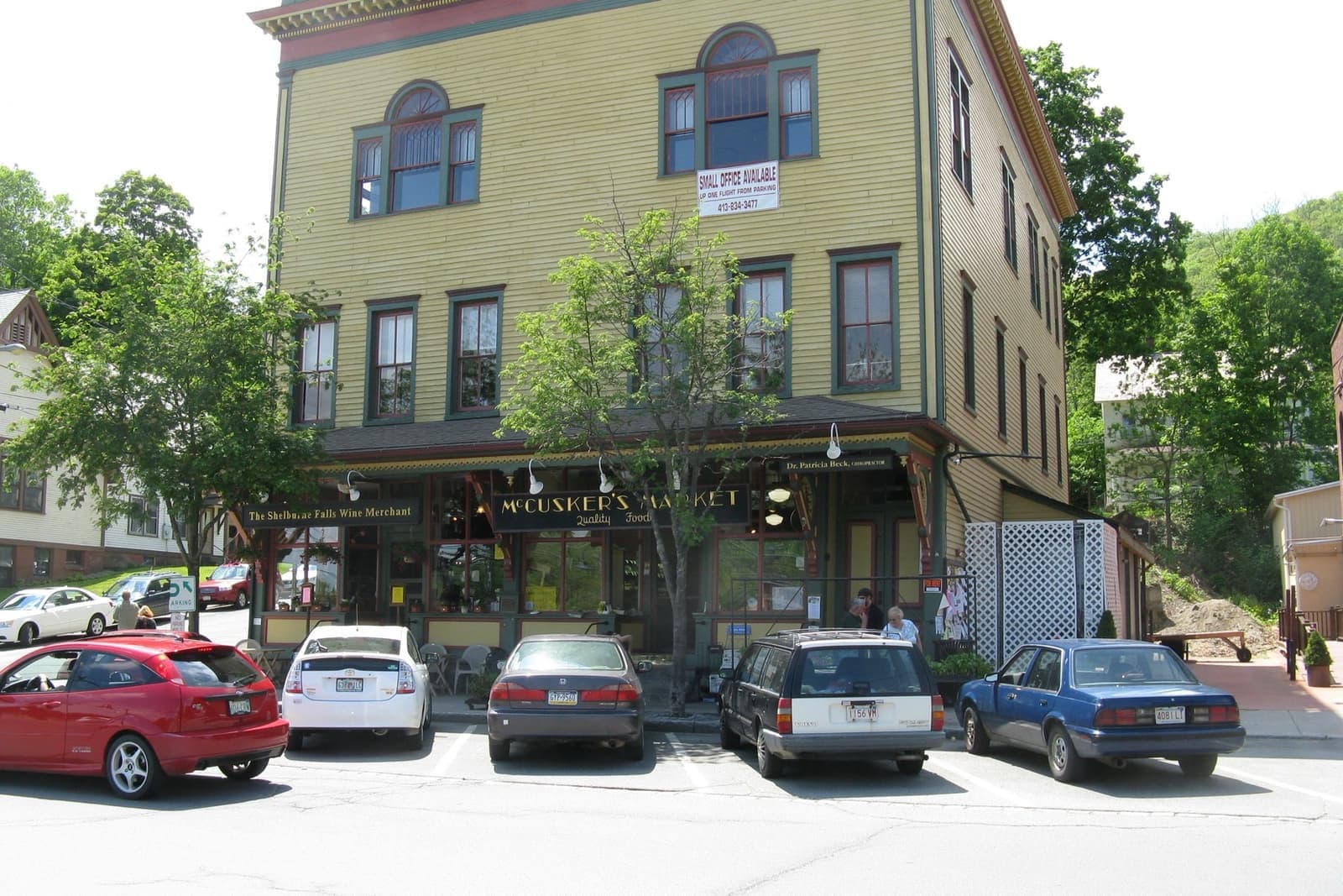 A green-painted corner shop with cars parked outside