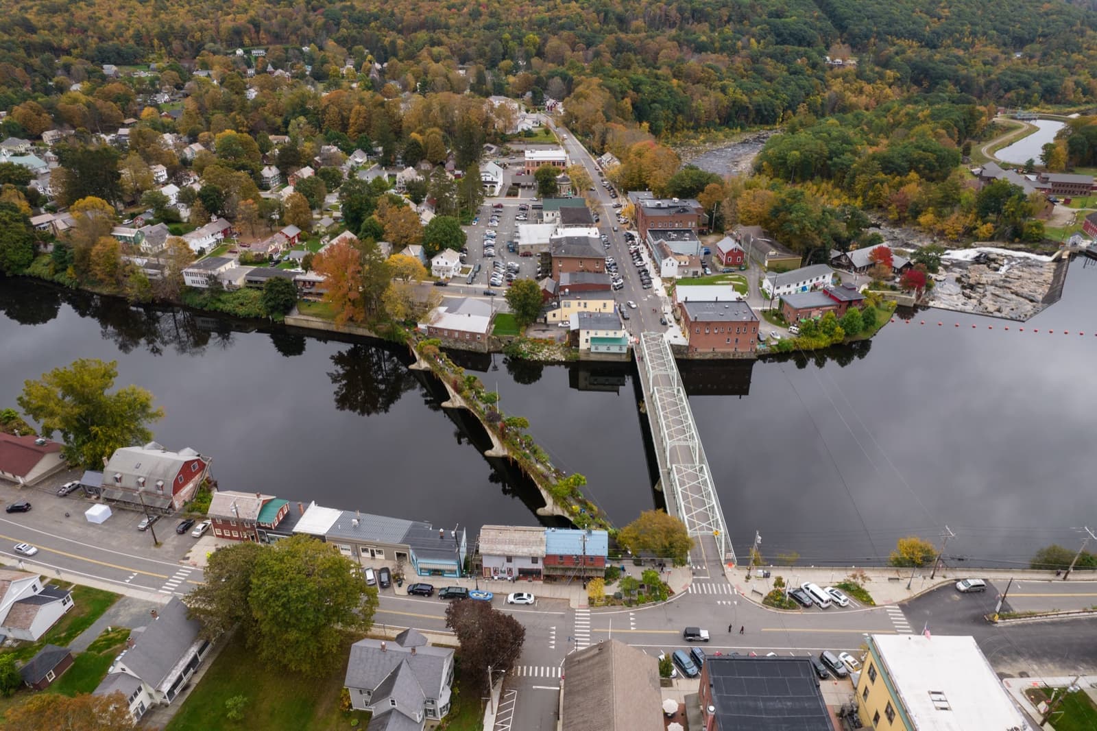 An aerial view of Shelburne Falls, its river and iron truss bridge in autumn