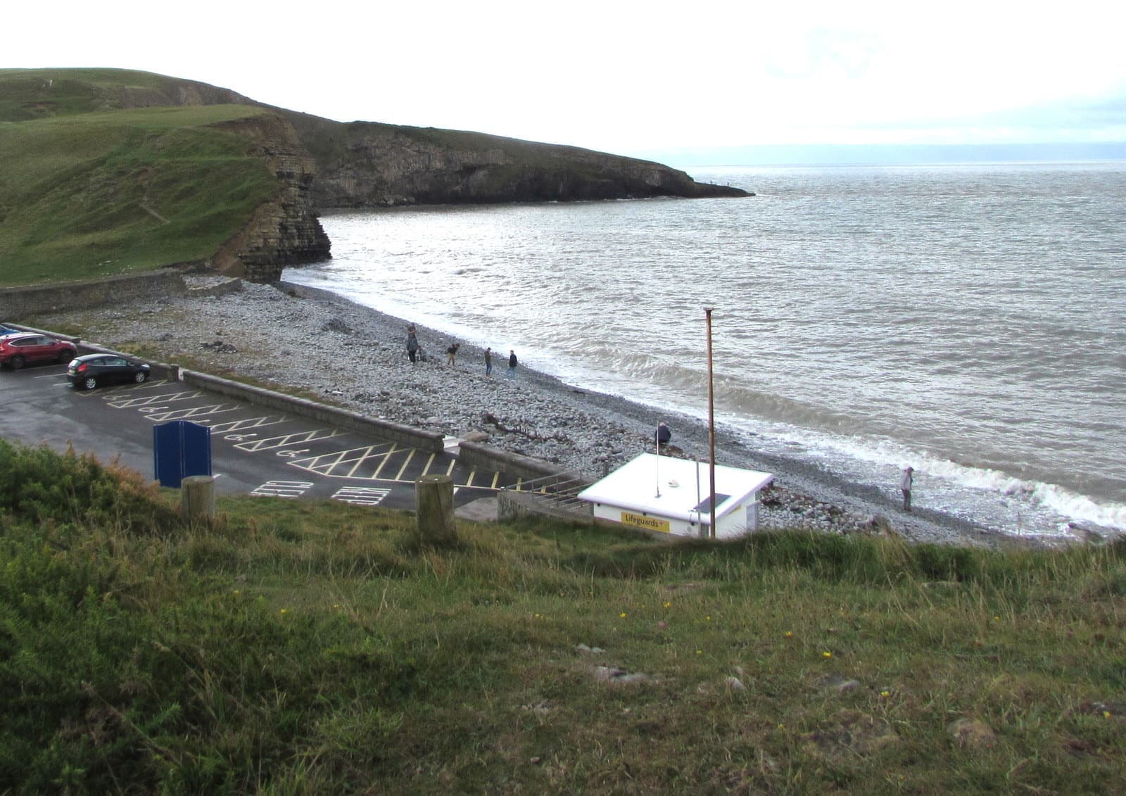 A curving beach below green cliffs at Dunraven Bay