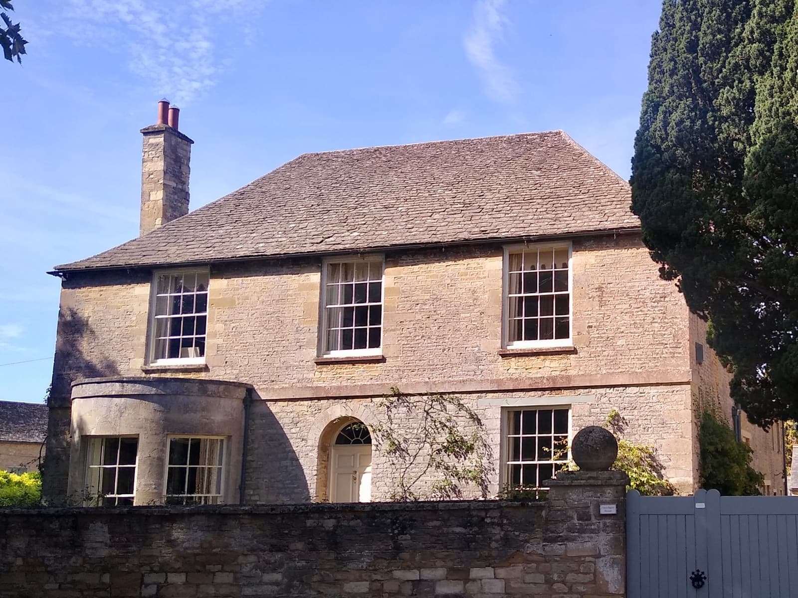 A stone house behind a wall beside the churchyard
