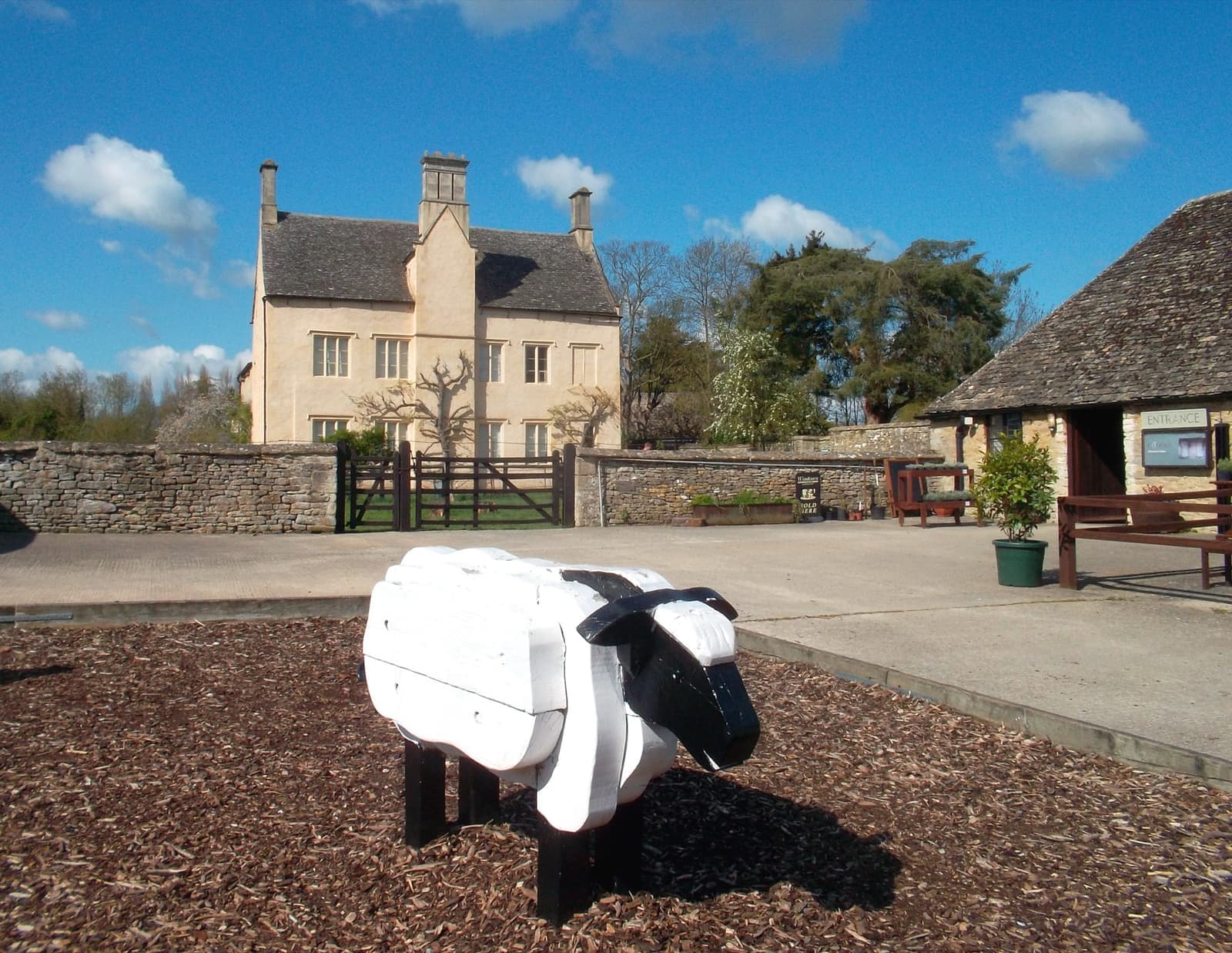 A gabled stone manor house with a farmyard in front