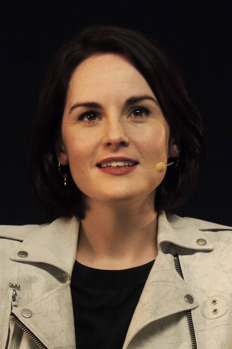 Michelle Dockery with short dark hair, speaking on stage