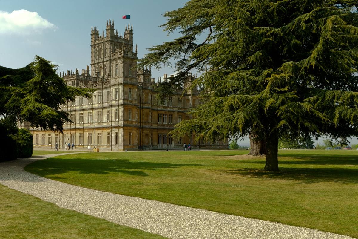 Highclere Castle beyond a lawn and a great cedar
