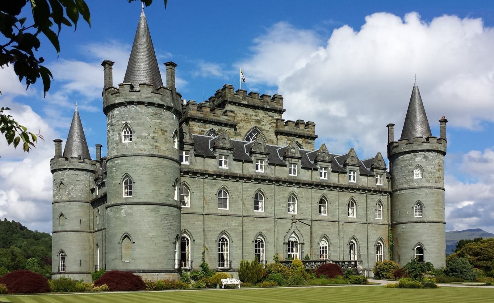 A grey-green stone castle with round corner turrets
