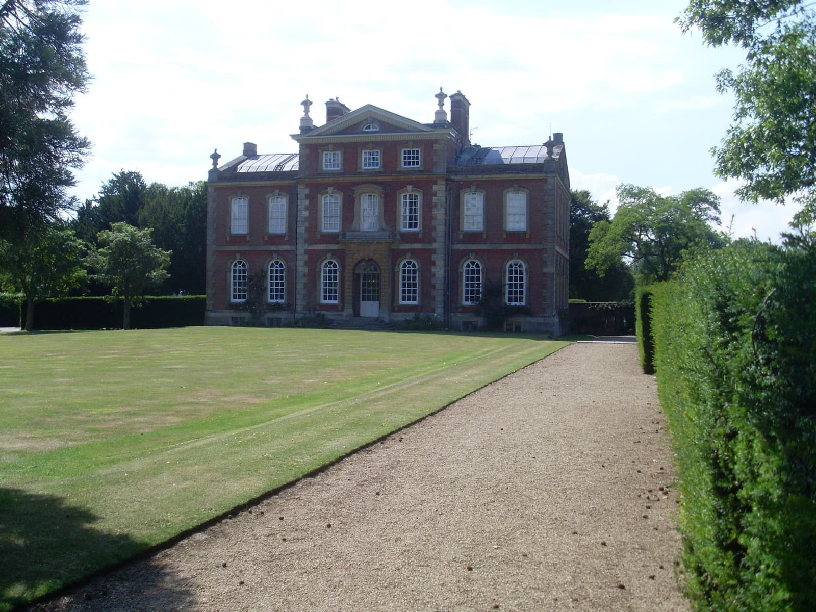 A red-brick country house with stone dressings and a lawn