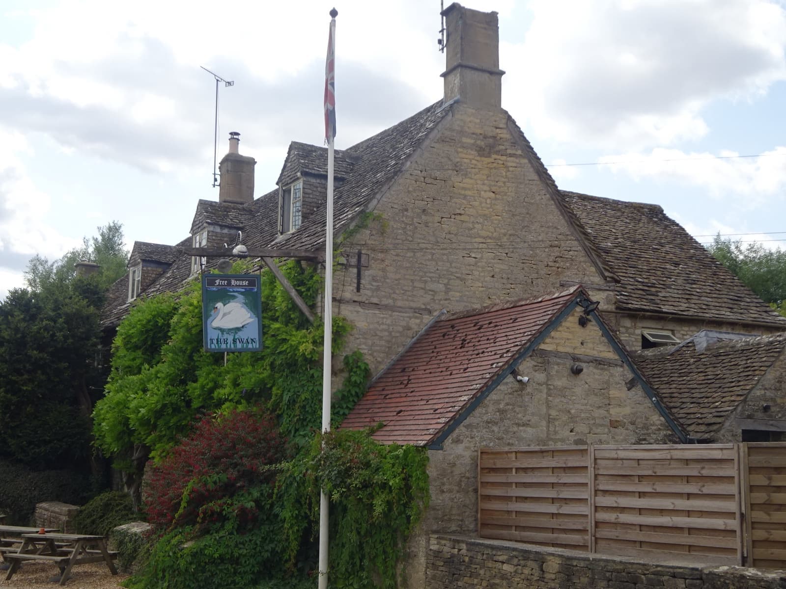 A stone inn with wisteria beside a river meadow