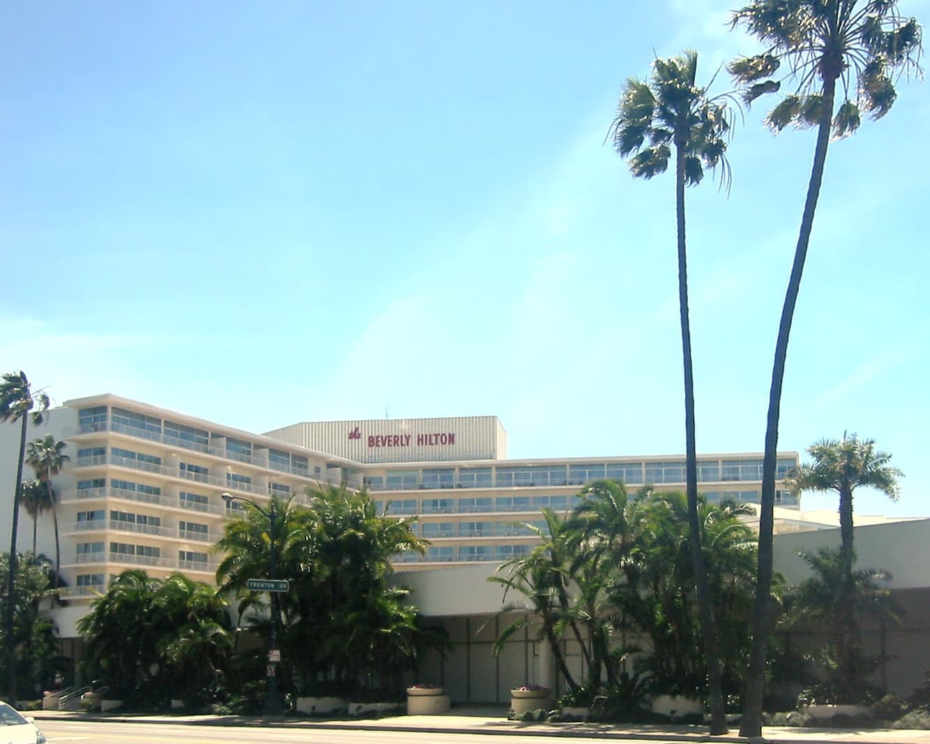A long modernist hotel behind tall palms