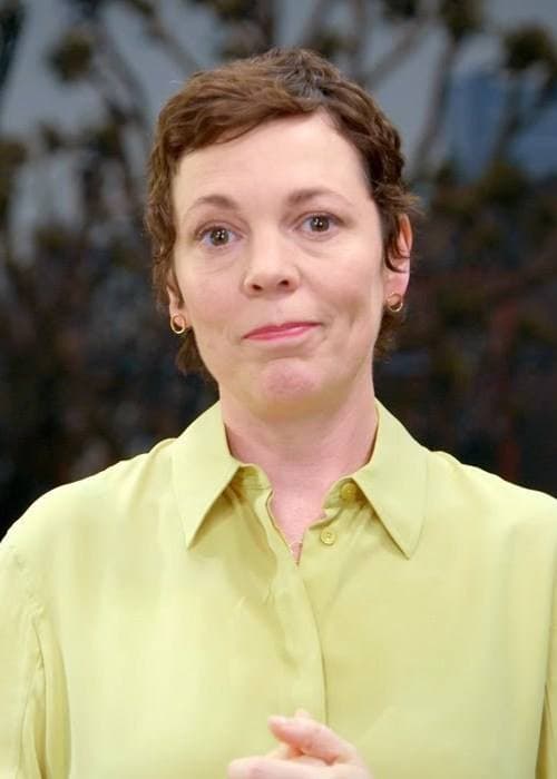 Olivia Colman with short brown hair in a pale yellow shirt, looking at the camera